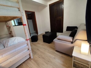 Una habitación con literas, un sofá, una mesita y un armario.