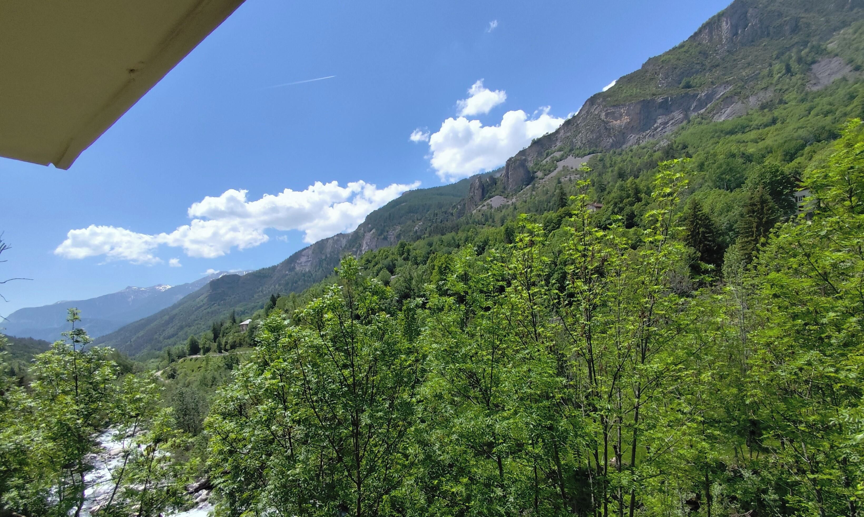 Un paisaje montañoso con vegetación verde y un cielo despejado.