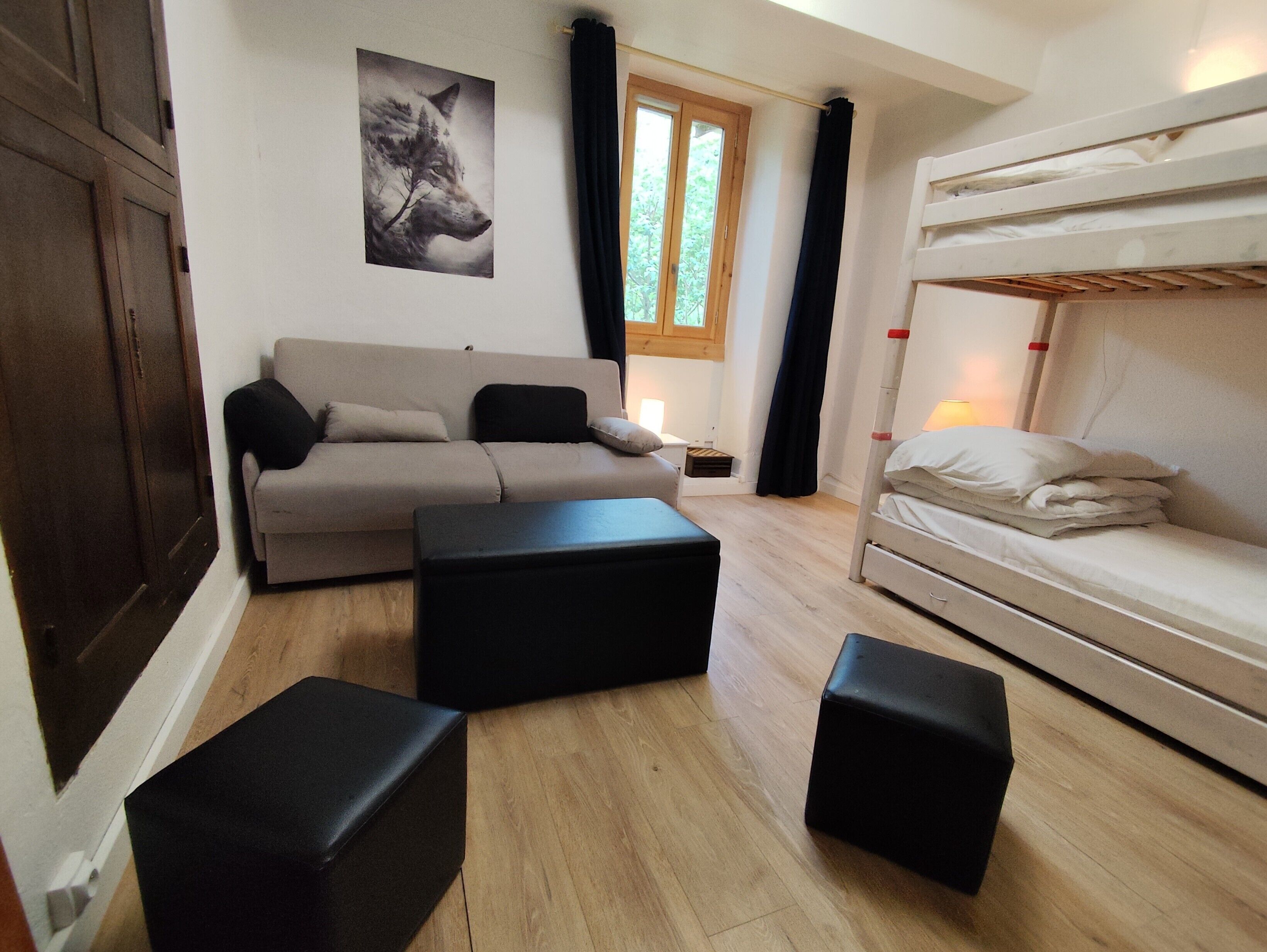 Une pièce comprenant un canapé, un lit, une table de chevet et une fenêtre avec des rideaux.
