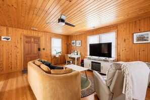 Ein Zimmer mit Holzwänden, einer Couch, einem Fernseher und einem Kamin.