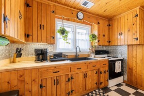 A kitchen with wooden cabinets, a coffee maker, a sink, and a stove. - The Avalon House-2 Blocks to Avalon Pier, Vintage OBX Charm, Flex Stays All Year! (Kill Devil Hills)