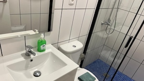 Une salle de bain avec un lavabo blanc, des toilettes et une douche à parois de verre.