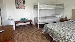Une chambre avec un lit superposé, un bureau, un banc et un tableau accroché au mur.