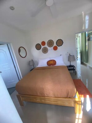 Ein Schlafzimmer mit Bett, Deckenventilator, Tür und Fenster.