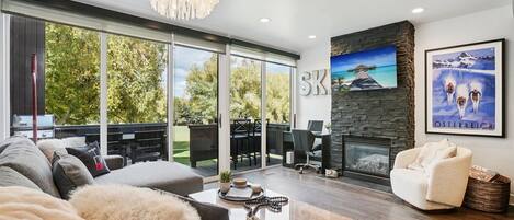 Una sala de estar moderna con chimenea, un ventanal y vistas al exterior.