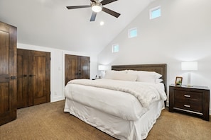 A bedroom with a large bed, wooden wardrobe, ceiling fan, and small windows. - Three Kings Luxury Townhome 2BR Walk to Ski - Spa Inspired Bath (Park City)