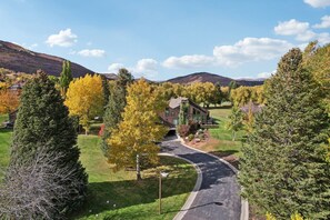 A residential area with a curved driveway leading to a house with a brown roof and a green lawn. - Three Kings Remodeled Townhome Walk to Ski 2BR/2BA Spa Inspired Primary Suite (Park City)