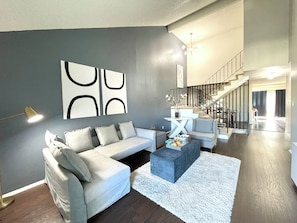A modern living room with a grey sofa, a coffee table, and a staircase leading to an upper level. - South San Francisco Sweet Home-10 minutes to SFO (South San Francisco)