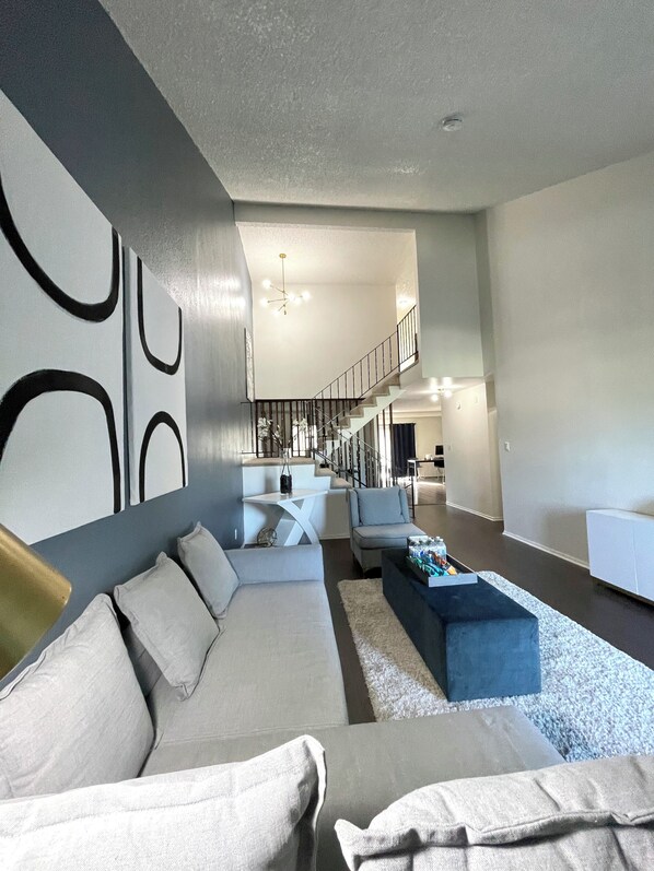 A modern living room with a sofa, a coffee table, and a staircase leading to an upper level. - South San Francisco Sweet Home-10 minutes to SFO (South San Francisco)