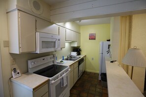 A compact kitchen with a microwave, stove, and sink. - One Bedroom with 2 living rooms at Inns of WV! (Waterville Valley)