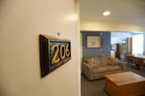 A room with a number plaque on the wall, a sofa, and a coffee table. - One Bedroom with 2 living rooms at Inns of WV! (Waterville Valley)