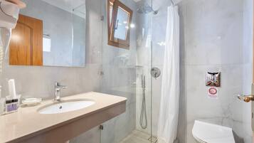 Une salle de bain moderne avec une douche à parois de verre, un lavabo avec un miroir et des toilettes.