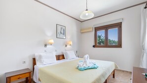 Habitación de hotel con cama, lámparas de noche, un cuadro, unidad de aire acondicionado, ventana con vistas y mesita de noche de madera.