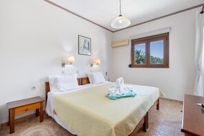 Ein Hotelzimmer mit einem Bett, Nachttischlampen, einem Gemälde, einer Klimaanlage, einem Fenster mit Blick und einem Holznachttisch.