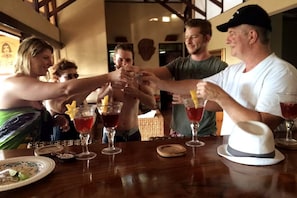 A group of people toasting with drinks at a wooden table in a room with exposed beams. - Ocho Villas (Coyolar)
