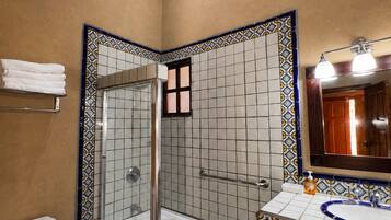 A bathroom with a shower, toilet, and sink, featuring patterned tiles and wooden beams.