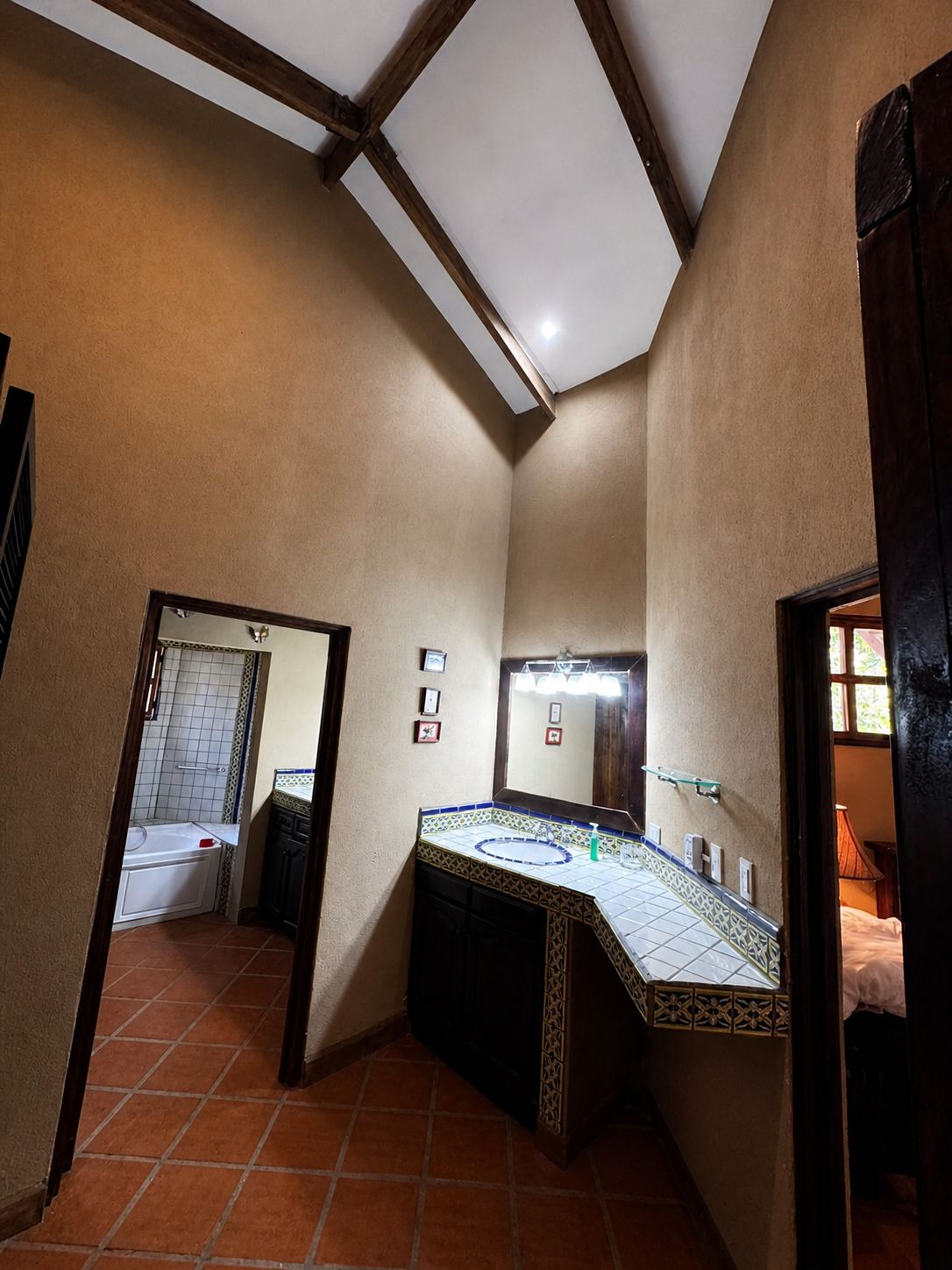 A bathroom with a tiled floor, a sink with a patterned countertop, a mirror, and a shower area.