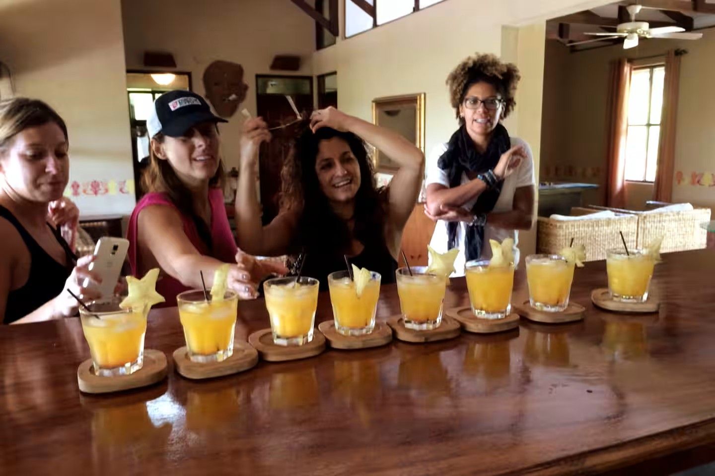 Un groupe de personnes est assis au bar, devant plusieurs verres d’une boisson jaune, dont certains sont décorés de morceaux de fruits.