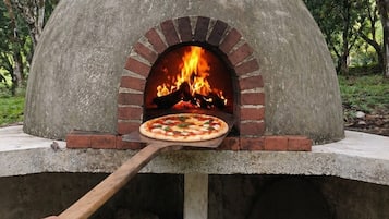 Un horno de pizza con interior de ladrillo y una pizza que se coloca en su interior.