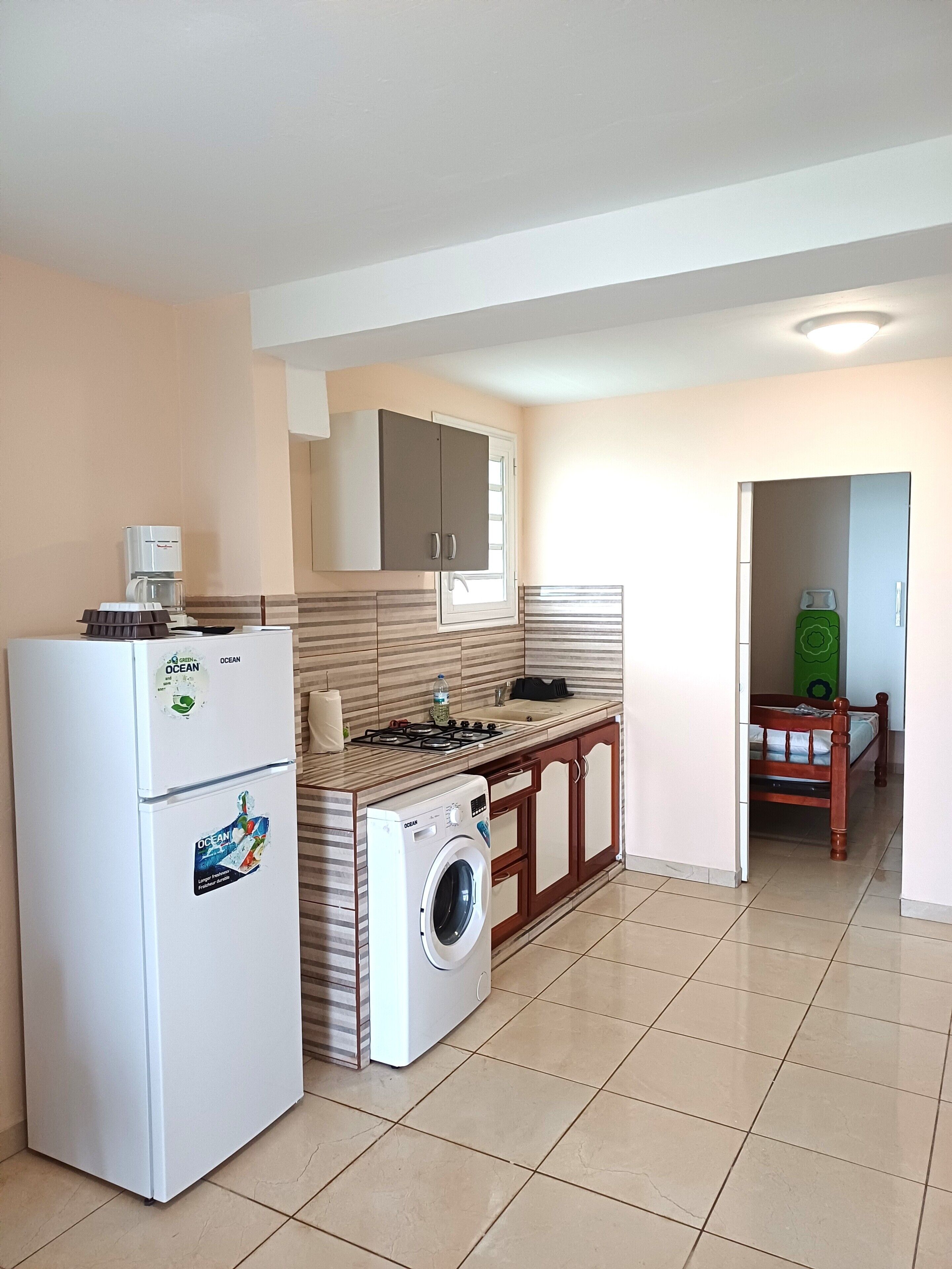 A compact kitchen with a refrigerator, washing machine, and a gas stove.