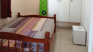 Une chambre à coucher avec un lit, une armoire et un petit meuble blanc.