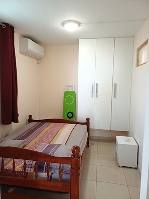 Een slaapkamer met een bed, een garderobe en een klein wit kastje.