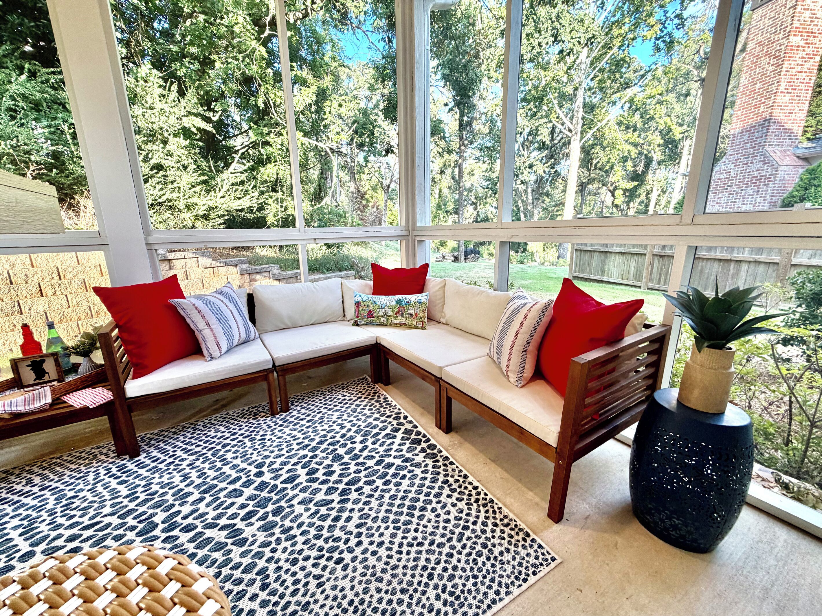 A sunlit room with a sectional sofa, a woven rug, and a potted plant.
