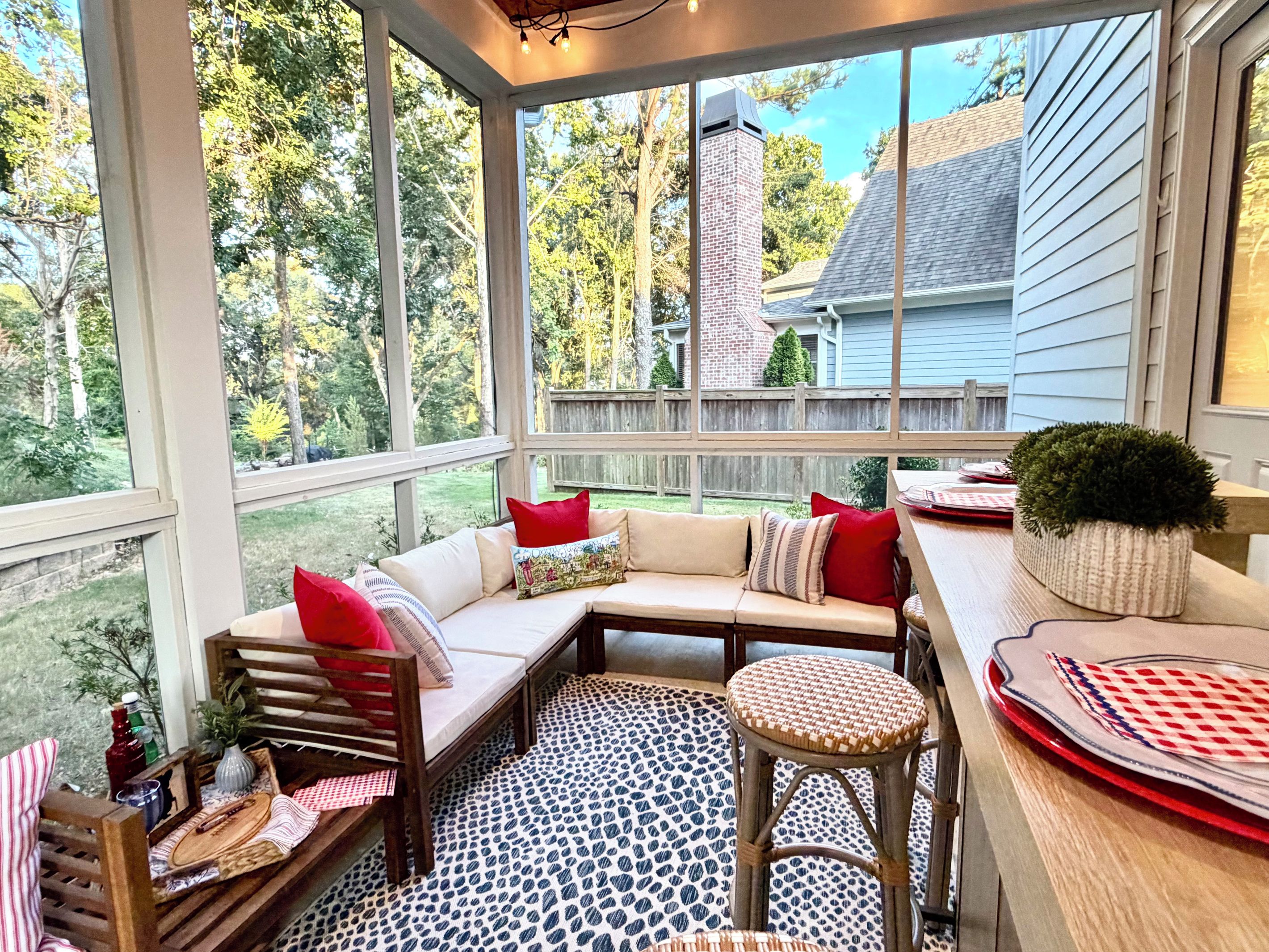 A covered porch with a cushioned seating area, a small table, and a potted plant.
