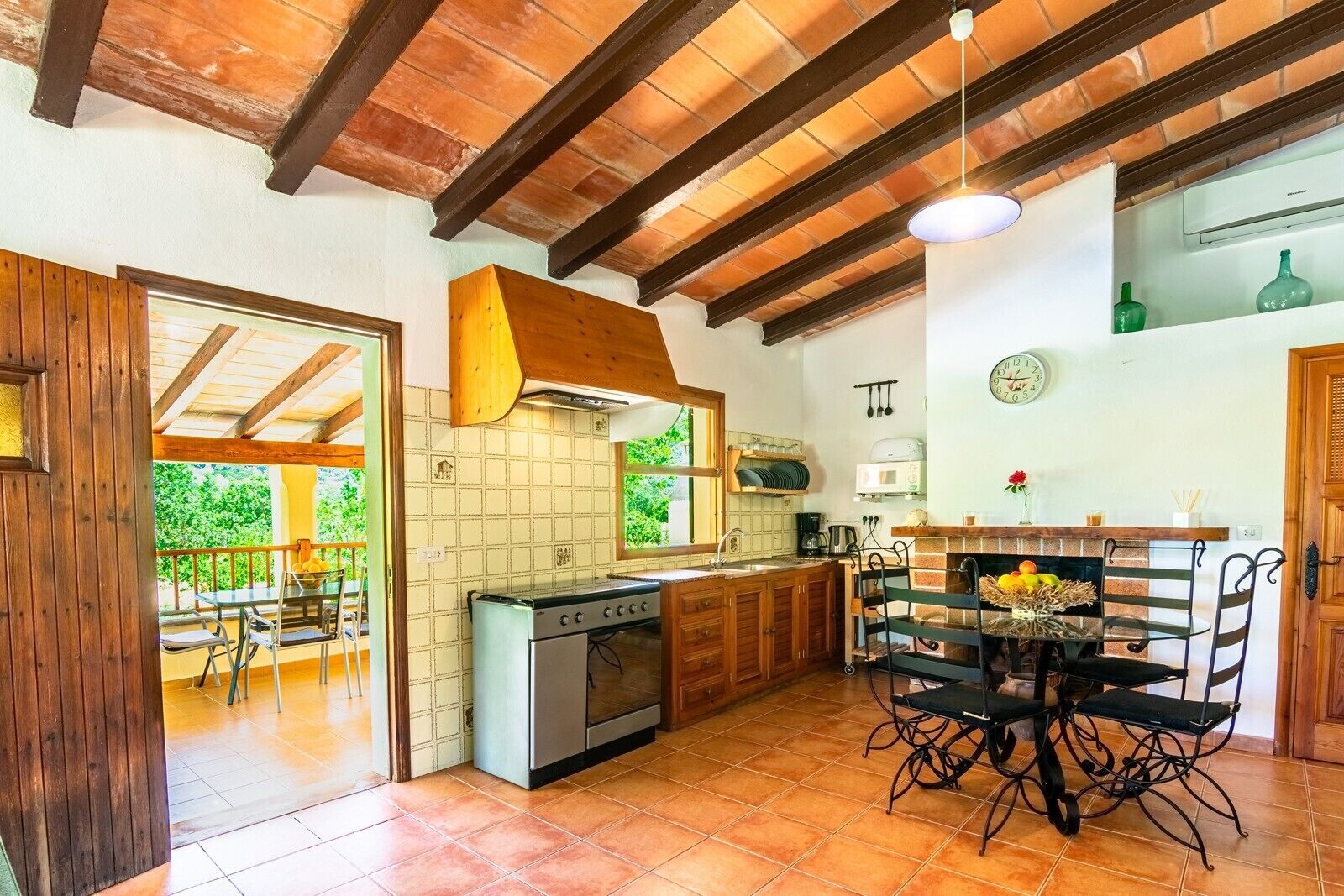 A kitchen with a stove, sink, and dining area with chairs.