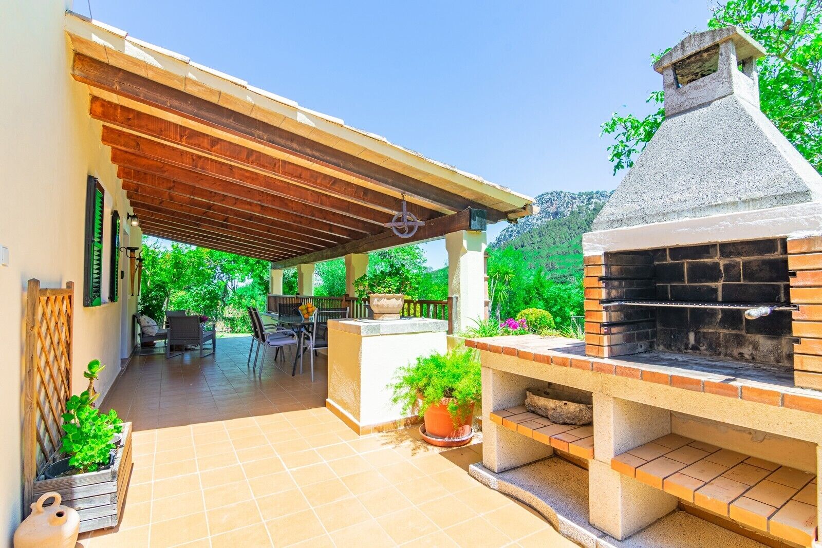 Un patio exterior con una parrilla, zona de estar y macetas.