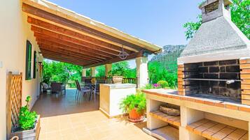 Un patio exterior con una parrilla, zona de estar y macetas.
