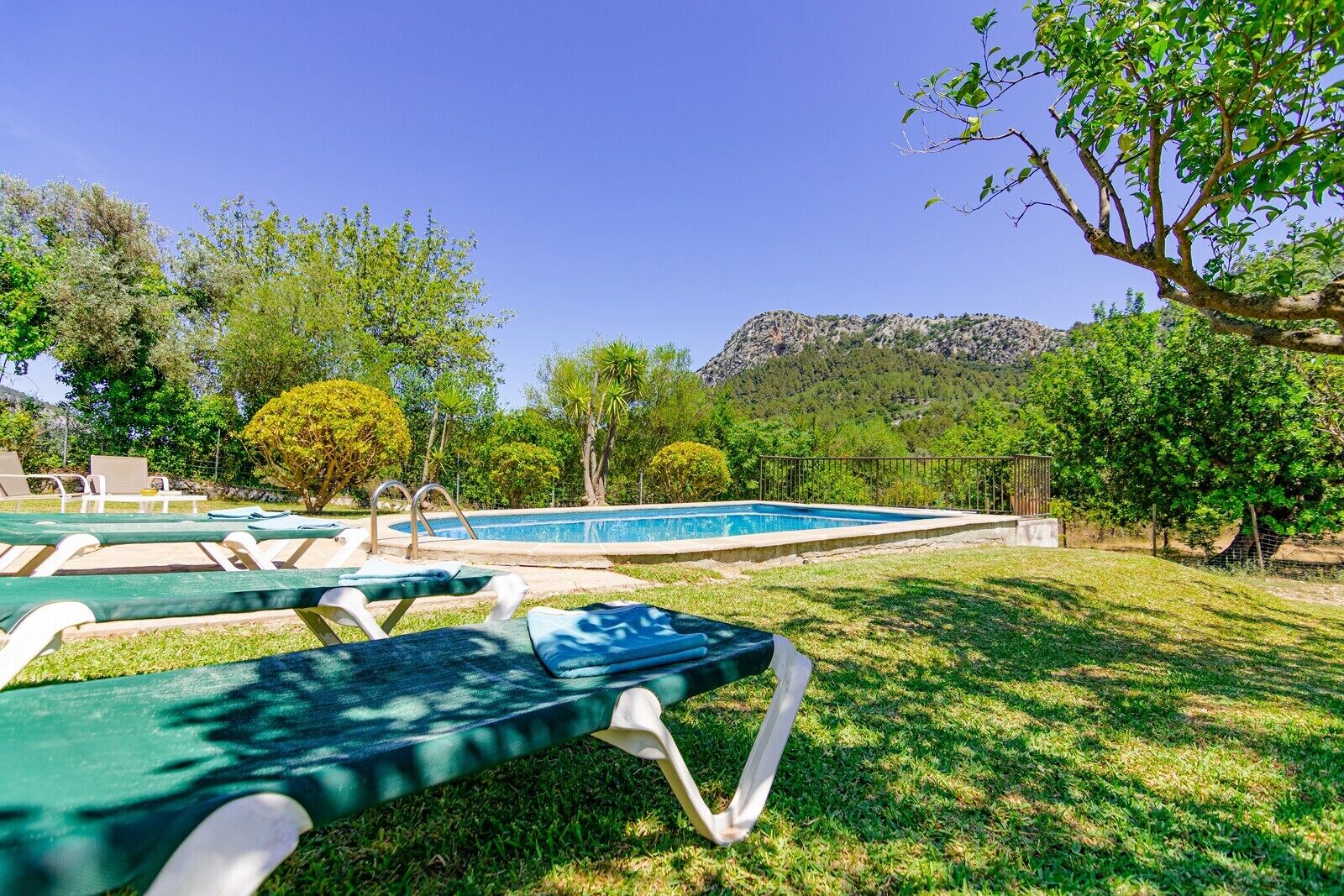 Zona de piscina con sillas de descanso y montañas al fondo.