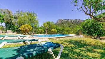 Zona de piscina con sillas de descanso y montañas al fondo.
