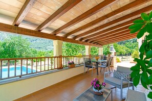 A covered patio with a pool, outdoor furniture, and a view of the surrounding greenery. - Can Pep – Country House in Pollensa with Pool (Pollenca)