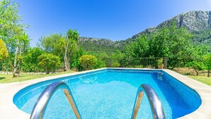 A clear blue swimming pool with a metal ladder, surrounded by greenery and mountains in the background. - Can Pep – Country House in Pollensa with Pool (Pollenca)