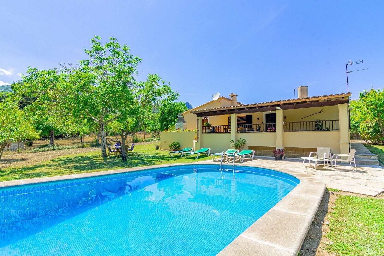 A swimming pool with lounge chairs and a covered patio area.