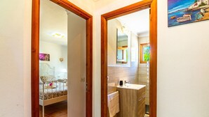 A hallway leading to a bedroom with a bed and a bathroom with a sink and mirror. - Can Pep – Country House in Pollensa with Pool (Pollenca)
