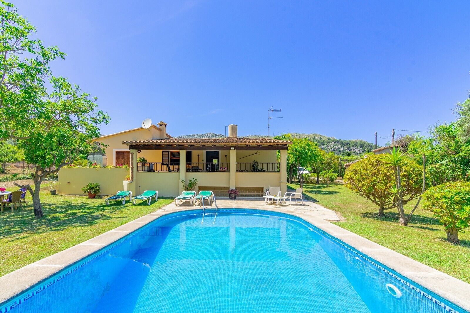 Una propiedad residencial con piscina, mobiliario de exterior y jardín.
