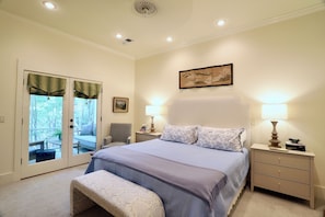A bedroom with a bed, bedside tables, a chair, a bench, and a view through a door to an outdoor area. - "Hillside Hideaway" by OVR (Oxford)