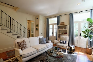 A living room with a white sofa, a glass coffee table, and a staircase. - "Hillside Hideaway" by OVR (Oxford)