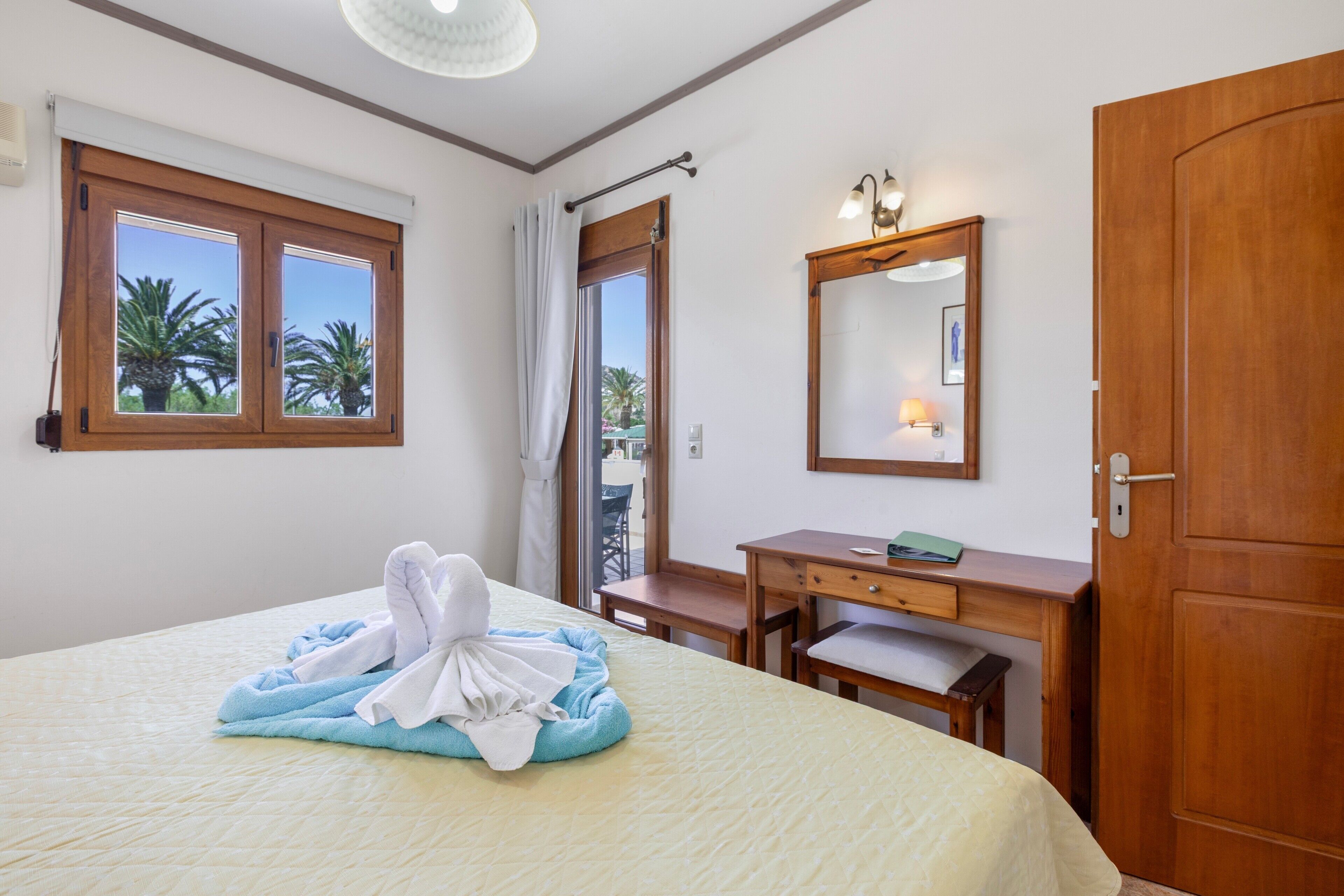 Ein Hotelzimmer mit Bett, Schreibtisch, Spiegel und Tür.