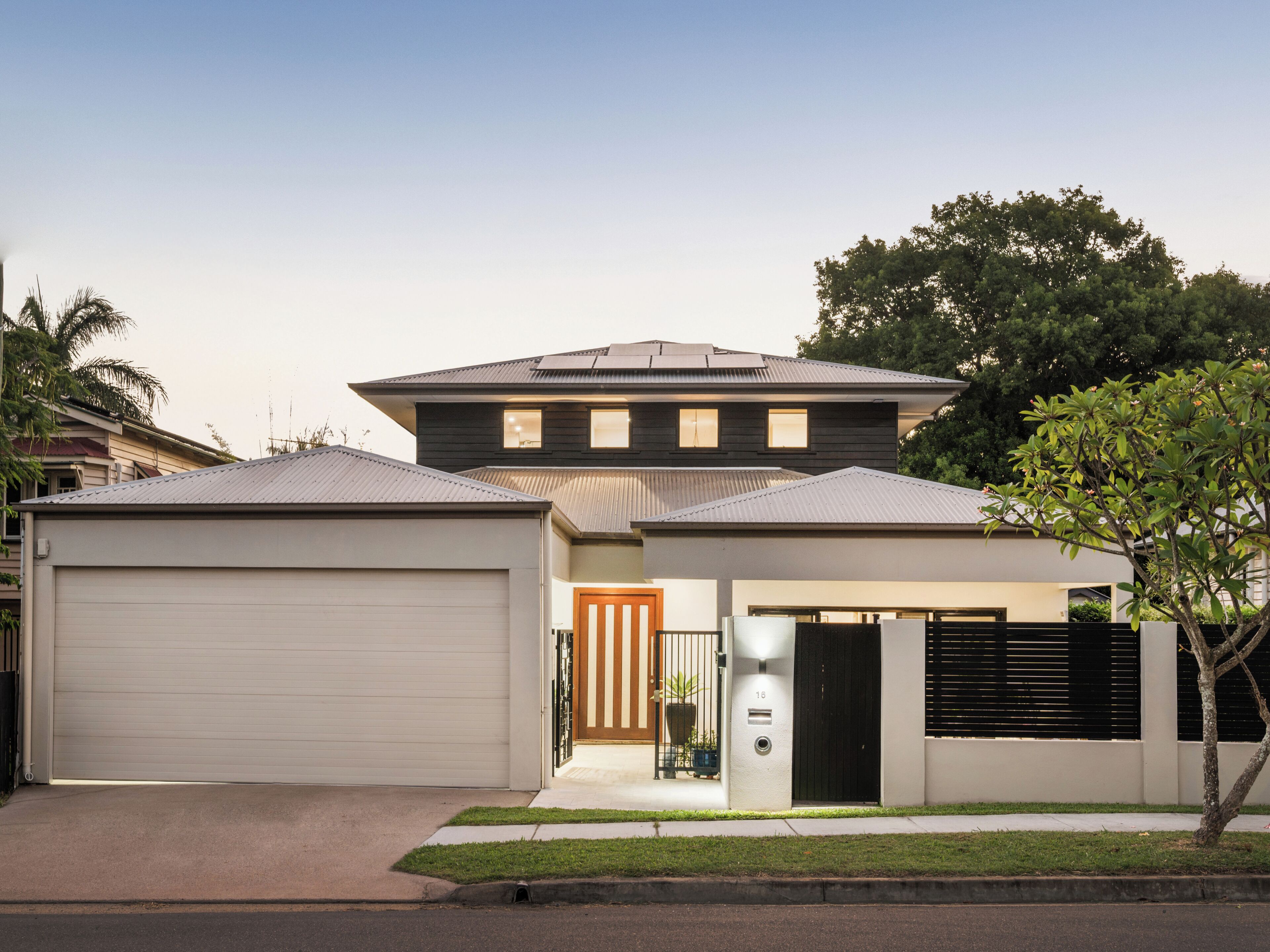 A modern two-story house with a garage, a front porch, and a small garden.