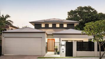 A modern two-story house with a garage, a front porch, and a small garden.