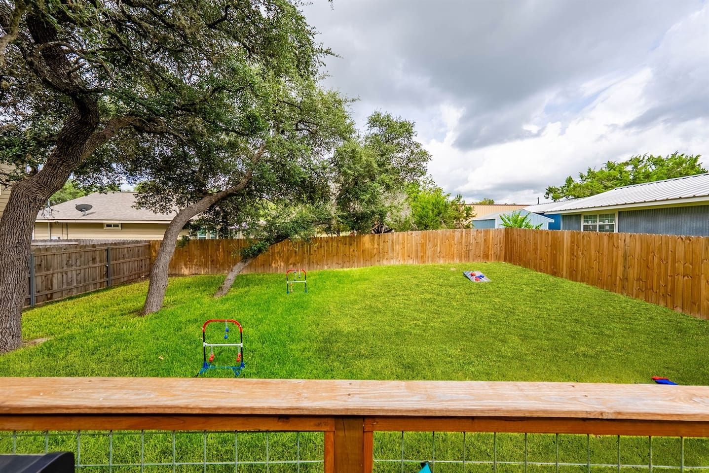 Un jardin avec une clôture en bois, une pelouse verdoyante et un arbre.