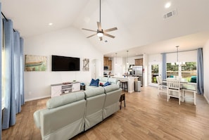 A spacious living area with a sofa, a dining table, and a kitchen in the background. - Near Boat Ramp #6 | Boat Parking + Huge Yard (Canyon Lake)