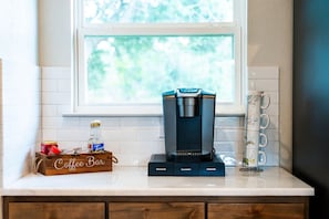 A coffee maker on a kitchen counter with a window above it, a coffee bar sign, and a mug rack. - Near Boat Ramp #6 | Boat Parking + Huge Yard (Canyon Lake)