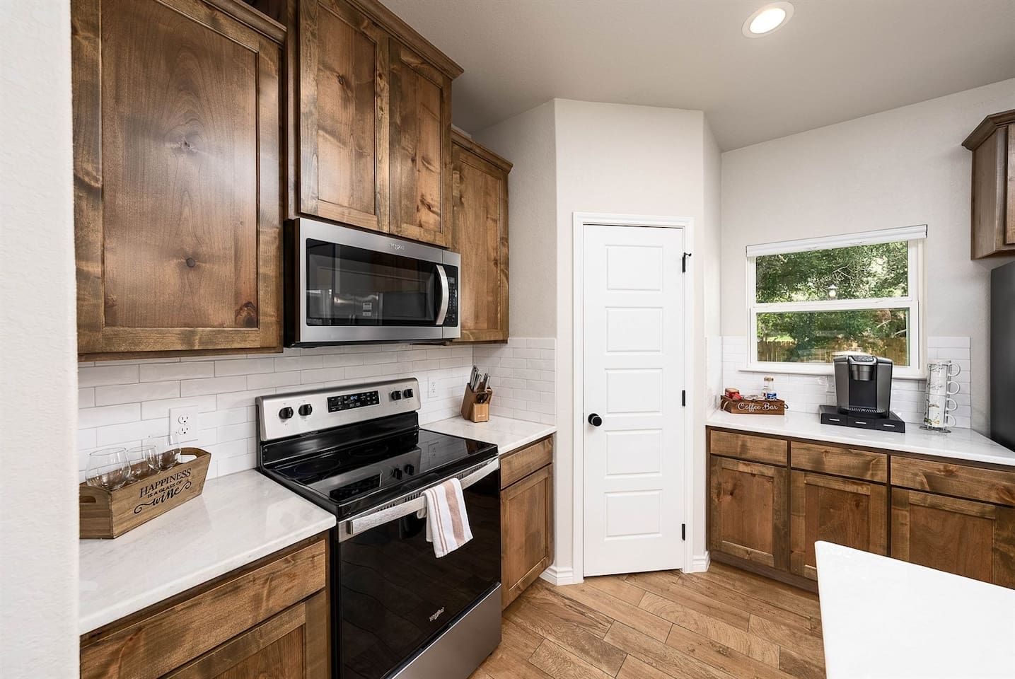 A kitchen with wooden cabinets, a stainless steel microwave, an oven, and a coffee maker on the counter.