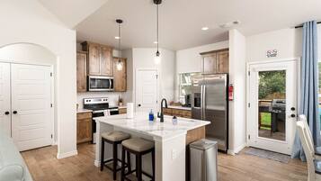 A modern kitchen with wooden cabinets, stainless steel appliances, and a central island with stools.