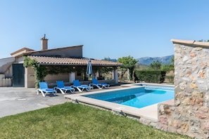 A swimming pool with lounge chairs, a pergola, and a stone wall. - Holiday Home "Catalina Petit" with Mountain View, Pool, Garden, Terrace & Wi-Fi (Pollença)
