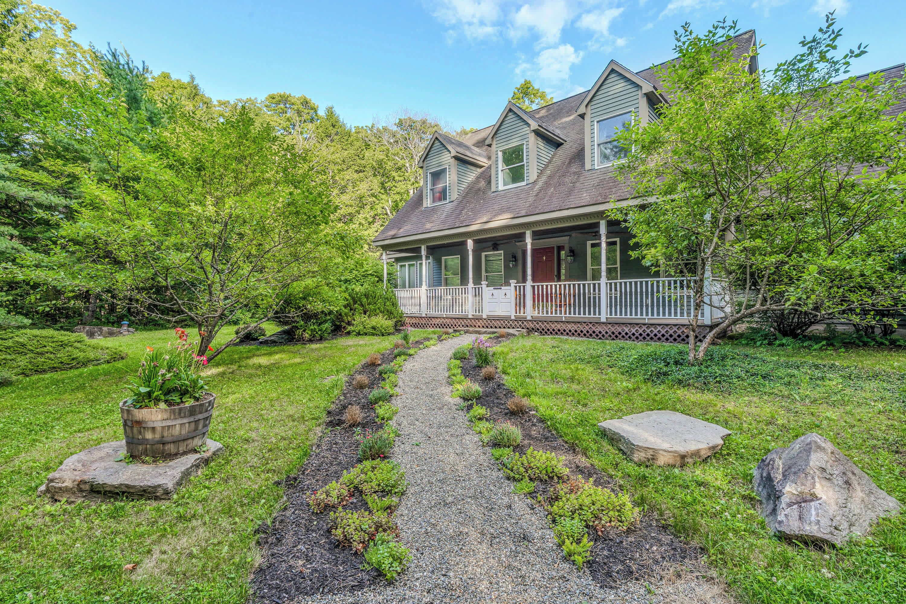 A two-story house with a covered porch and a gravel pathway leading to the front door.